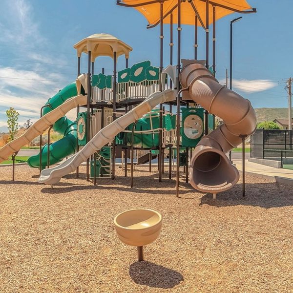 New Play structure with multiple slides, a sail for shade and three levels with certified playground chips covering the ground - certified playground bark chips